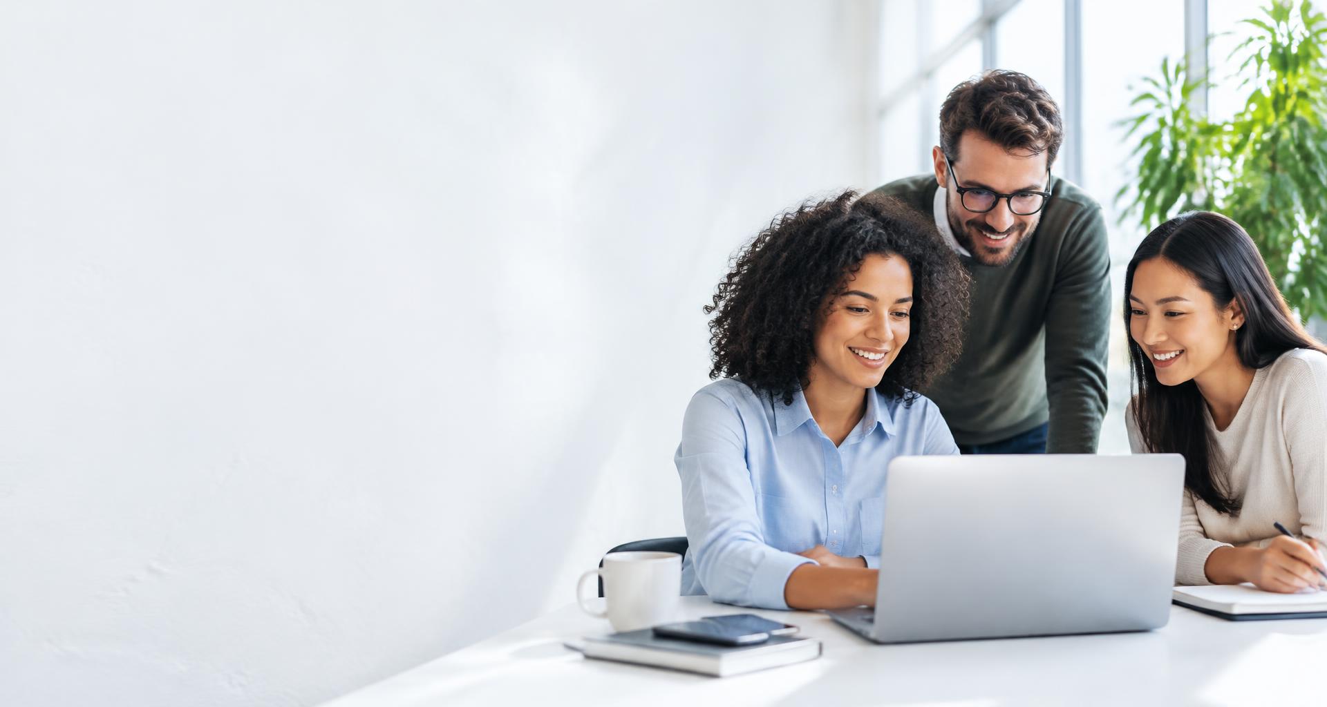 Colleagues working together at a laptop in a bright workplace
